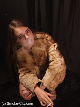 Красотка в шубе курит перед камерой и светит сиськами на фотографиях